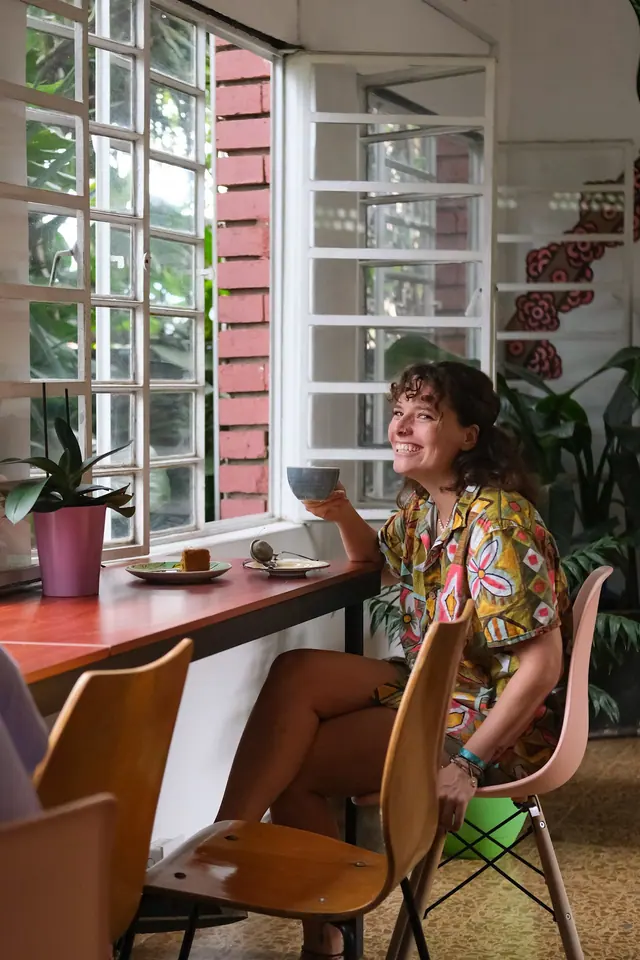 A guest smiling over a coffee at the café's window counter.