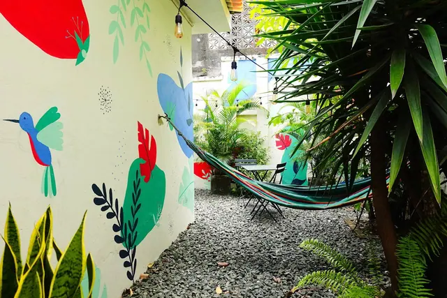 A gravel garden path with a hammock and a mural of a hummingbird and red flowers.