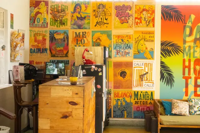 The lobby's wall of Cali letterpress-style posters and the rainbow La Palmera mural behind the wooden reception desk.