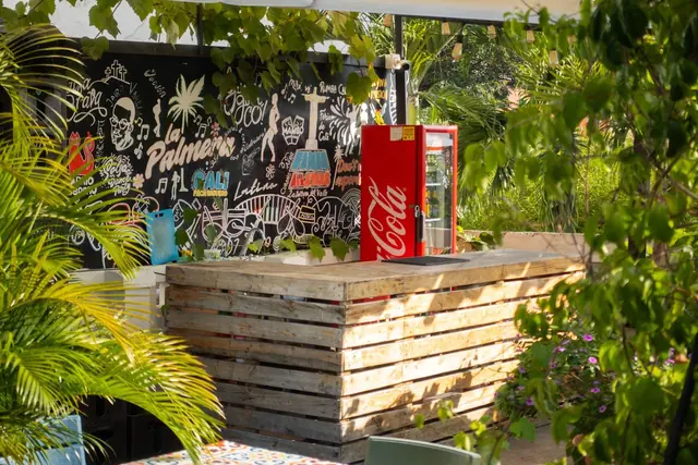 The rooftop bar: a pallet-wood counter in front of a chalk-style mural lettered 'La Palmera'.